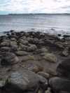 The section of the shore with boulders running into the water. The water is low. The section of the shore with boulders running into the water. The water is low.